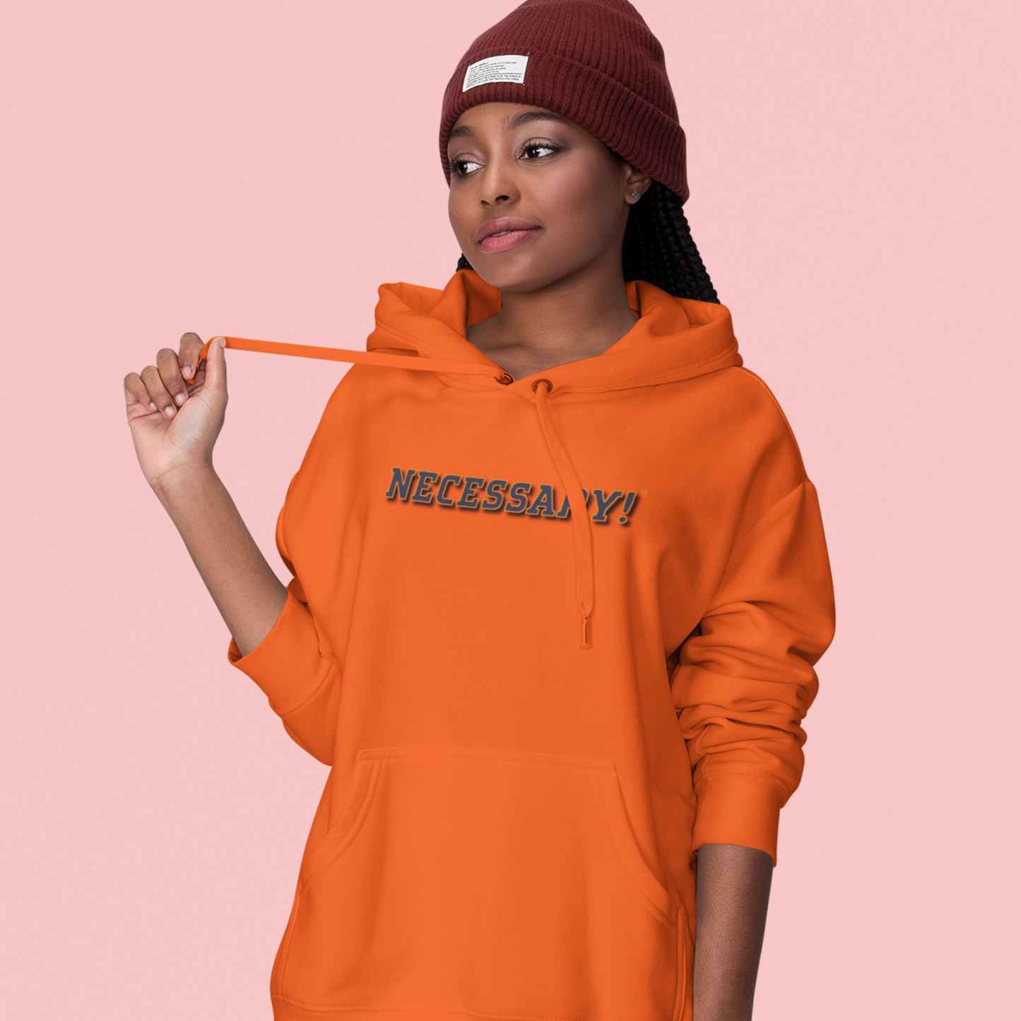 Person wearing an orange hoodie with 'NECESSARY!' text on a pink background
